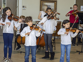 Three children playing violin